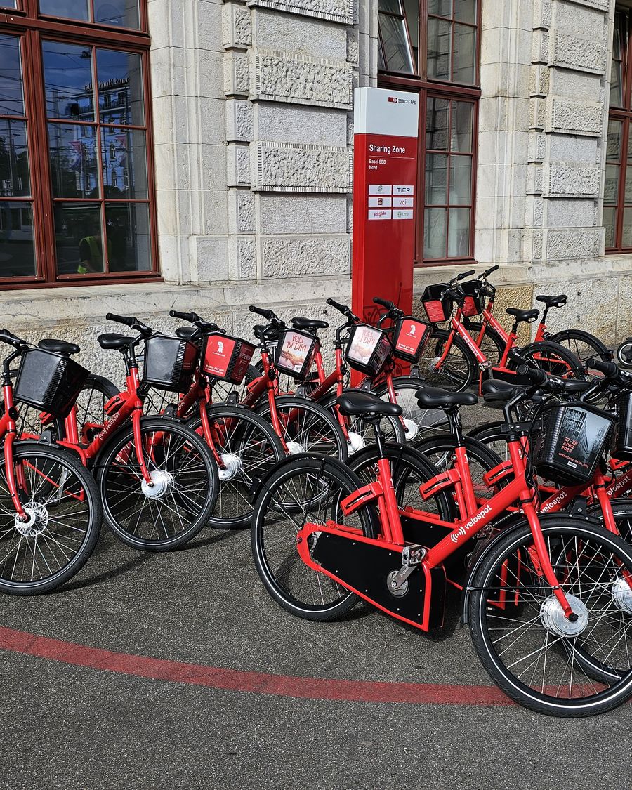 A row of red PubliBike Velospot pedelecs in front of Basel SBB station